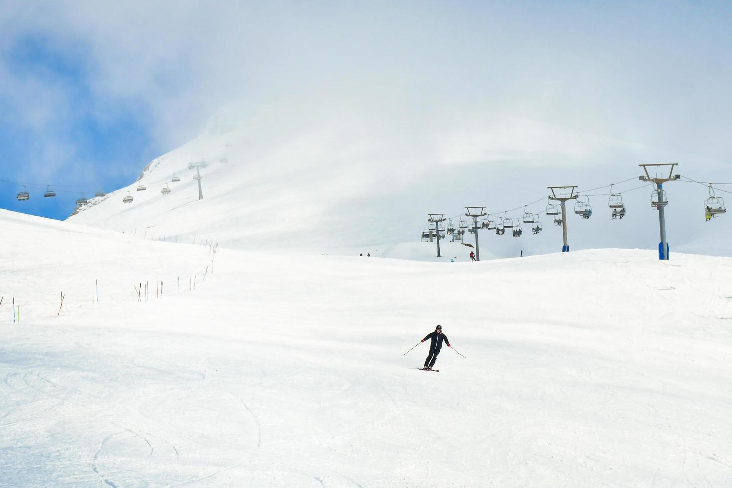 Low angle front view Male person alone skiing downhill in white snowy background. Bad visibility and solo adventure in mountains photo