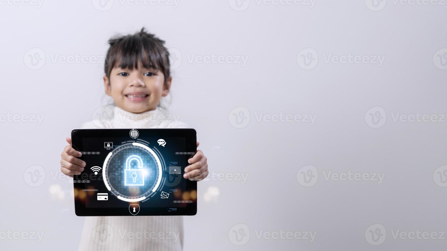 Child safety online. Little girl using tablet at home. icon of internet blocking app on foreground photo