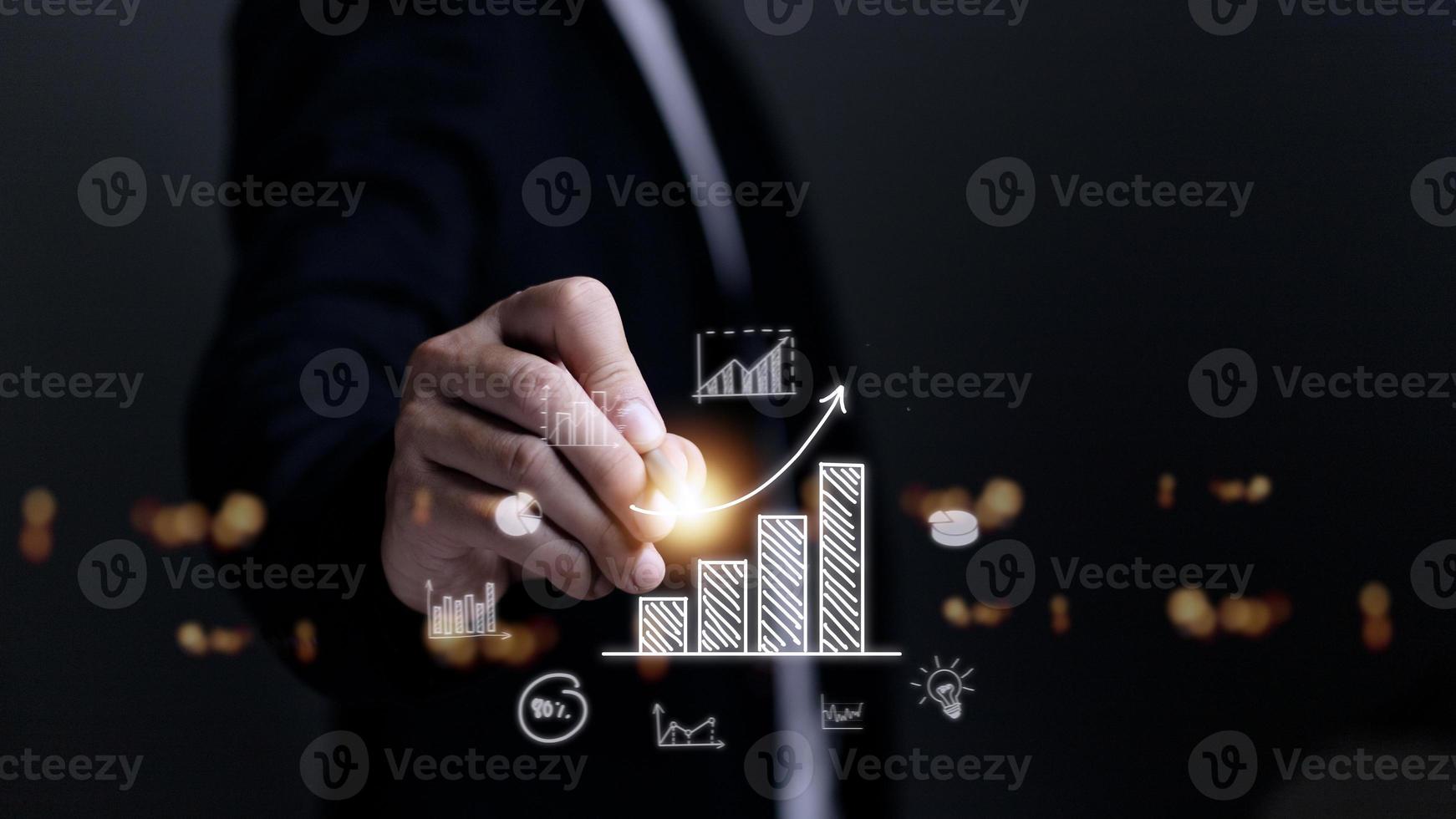 Businessman draws an increasing trend arrow and a rising chart from plan to goal. It is a representation of the idea of corporate investment development. photo