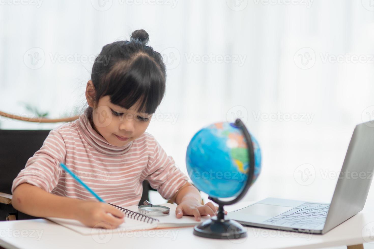 Asian little girl is learning the globe model, concept of save the world and learn through play activity for kid education at home. photo