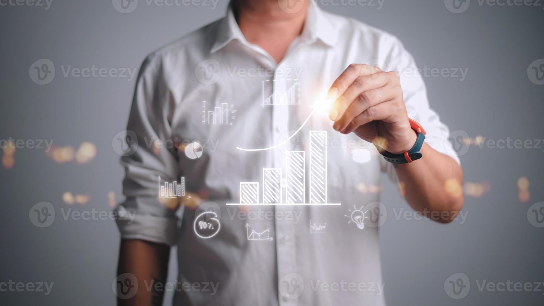 Businessman draws an increasing trend arrow and a rising chart from plan to goal. It is a representation of the idea of corporate investment development. photo