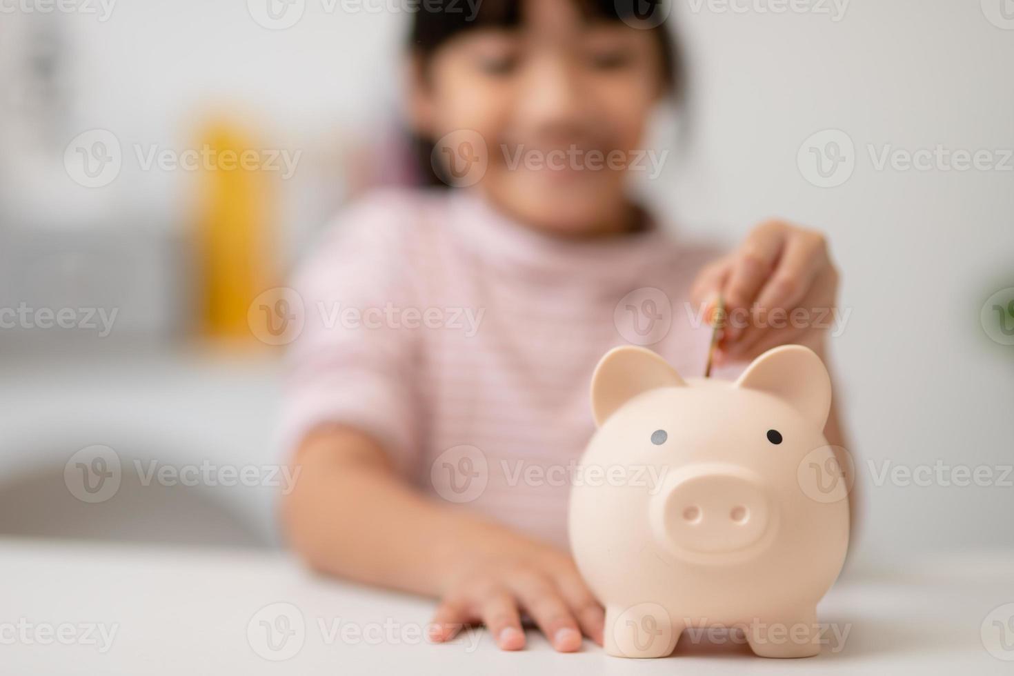 Little Asian girl saving money in a piggy bank, learning about saving, Kid save money for future education. Money, finances, insurance, and people concept photo