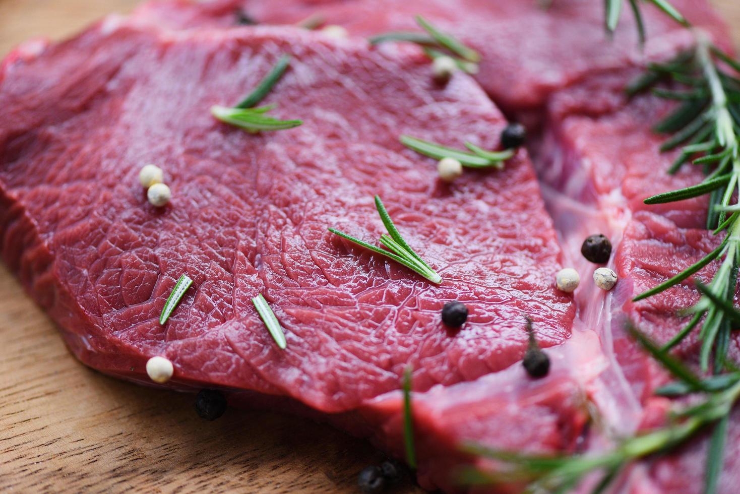 romero de carne de res cruda en una tabla de cortar de madera en la mesa de la cocina para cocinar filete de res asado o a la parrilla con ingredientes hierbas y especias proteína animal de res fresca foto