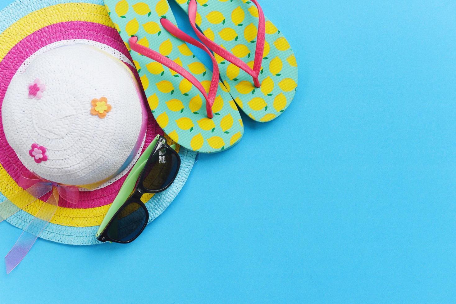 artículos de concepto de fondo de viaje accesorios de viaje de verano con gafas de sol sombrero chanclas para viajeros sobre fondo azul foto