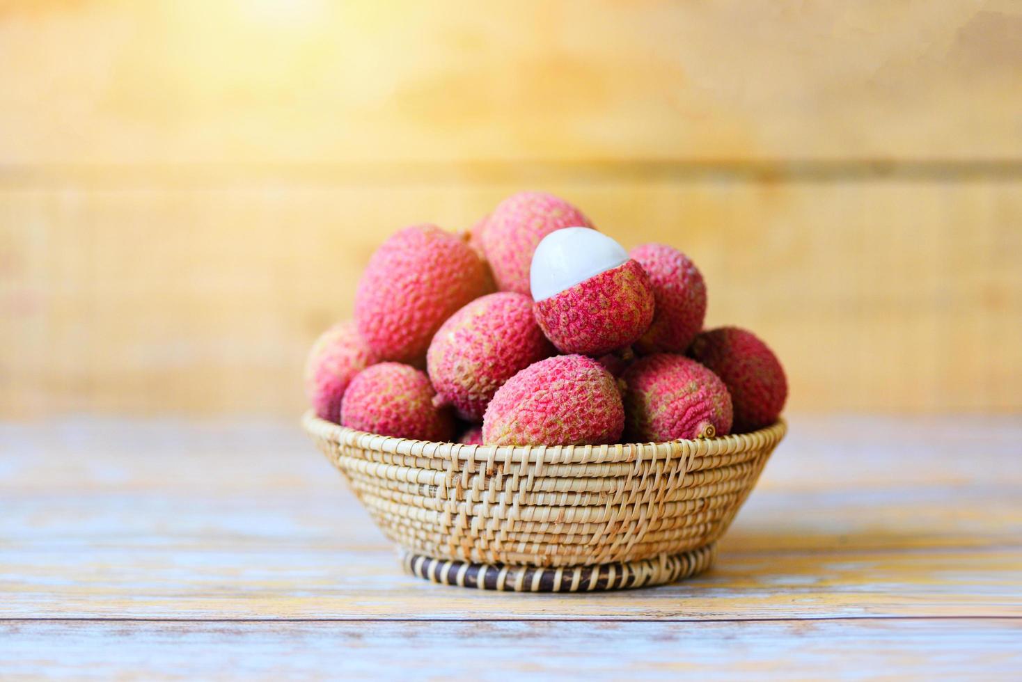 rodaja de lichi pelada sobre fondo de madera - cosecha de lichi fresca en cesta de verano de frutas tropicales de árboles en Tailandia foto