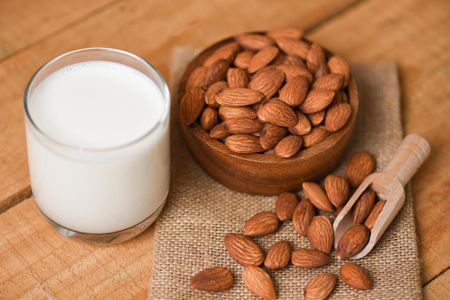 vaso de leche de almendras para el desayuno comida saludable - nueces de almendras en un tazón de fondo de madera foto