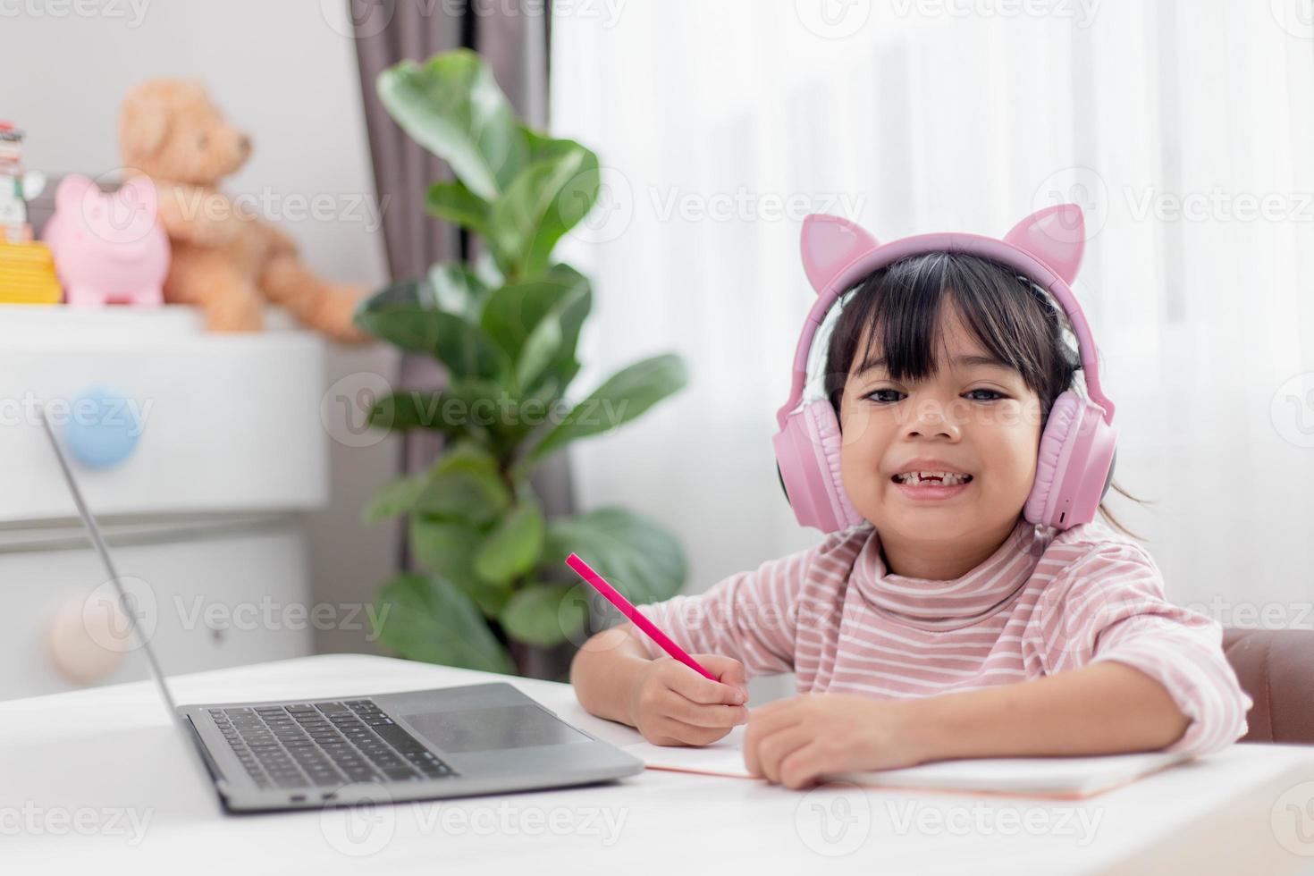 Asian little girl in headphones have video call distant class with teacher using laptop, study online on computer, homeschooling concept photo