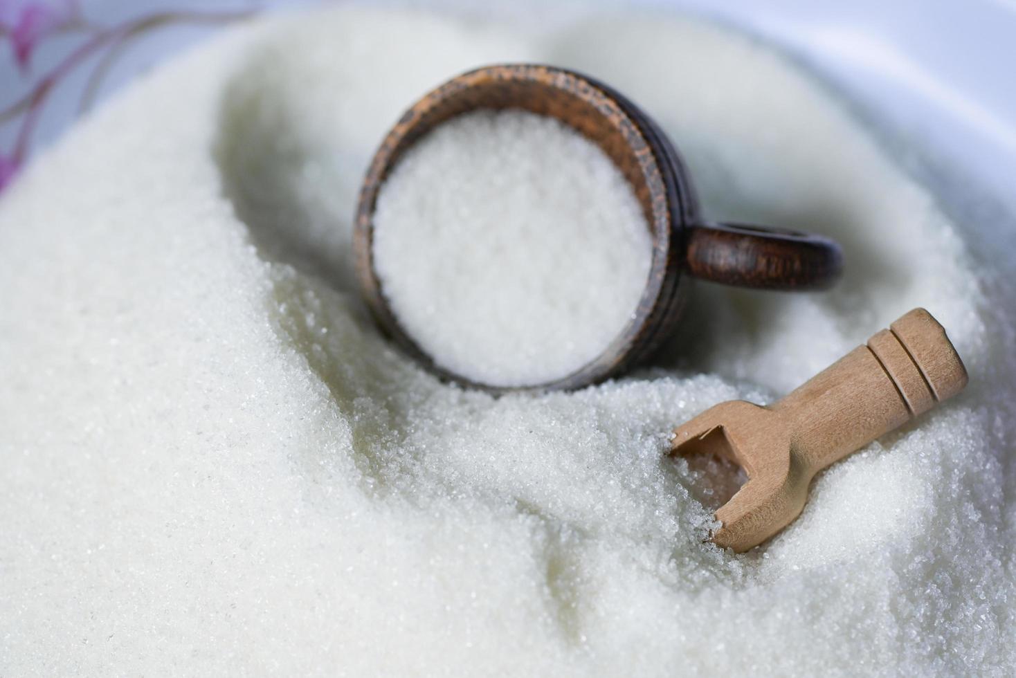 azúcar con taza y cuchara de madera, azúcar blanco para alimentos y dulces dulces de postre montón de azúcar dulce granulado cristalino foto