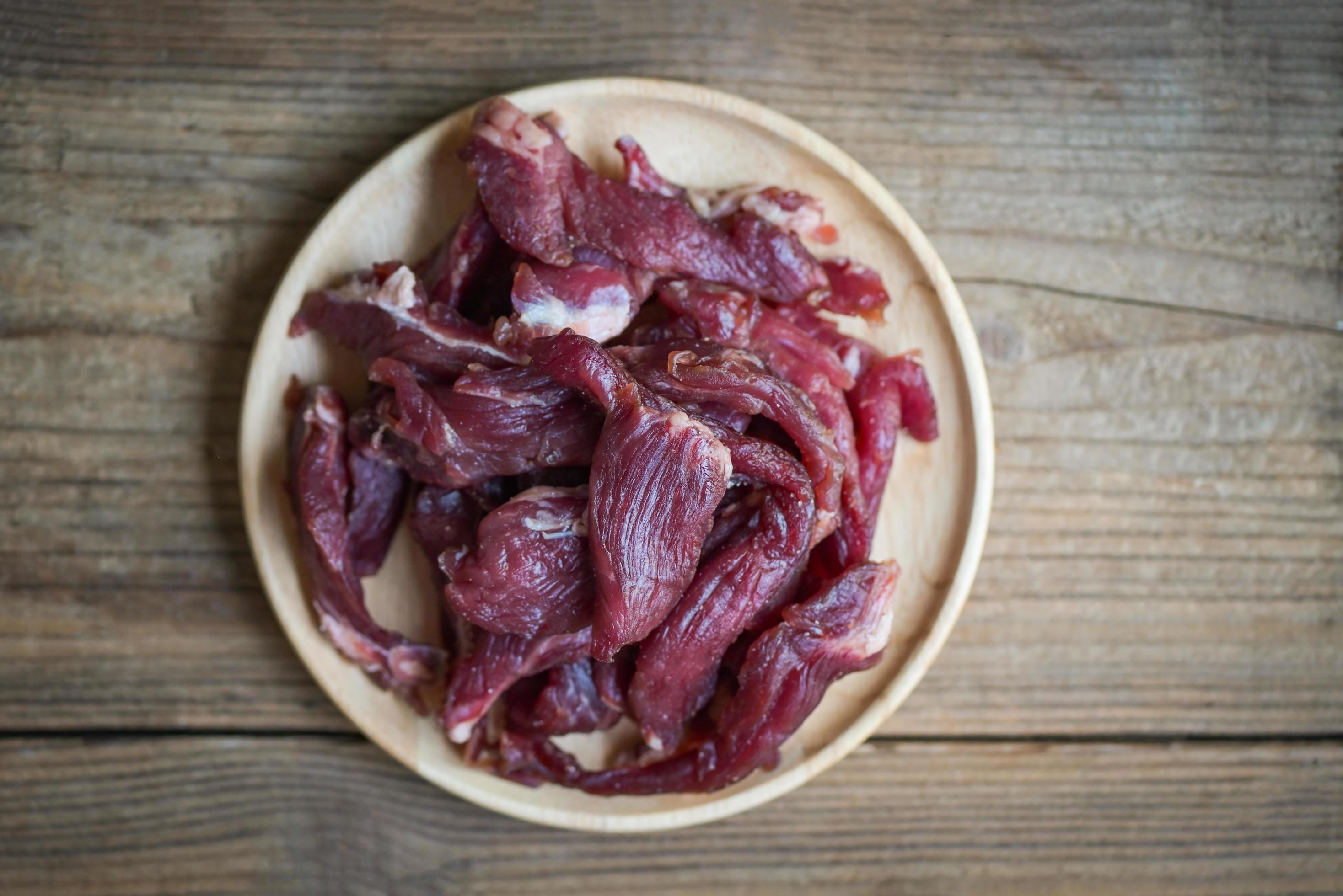 beef jerky on wooden plate, raw dried meat for cooking, dry meat beef