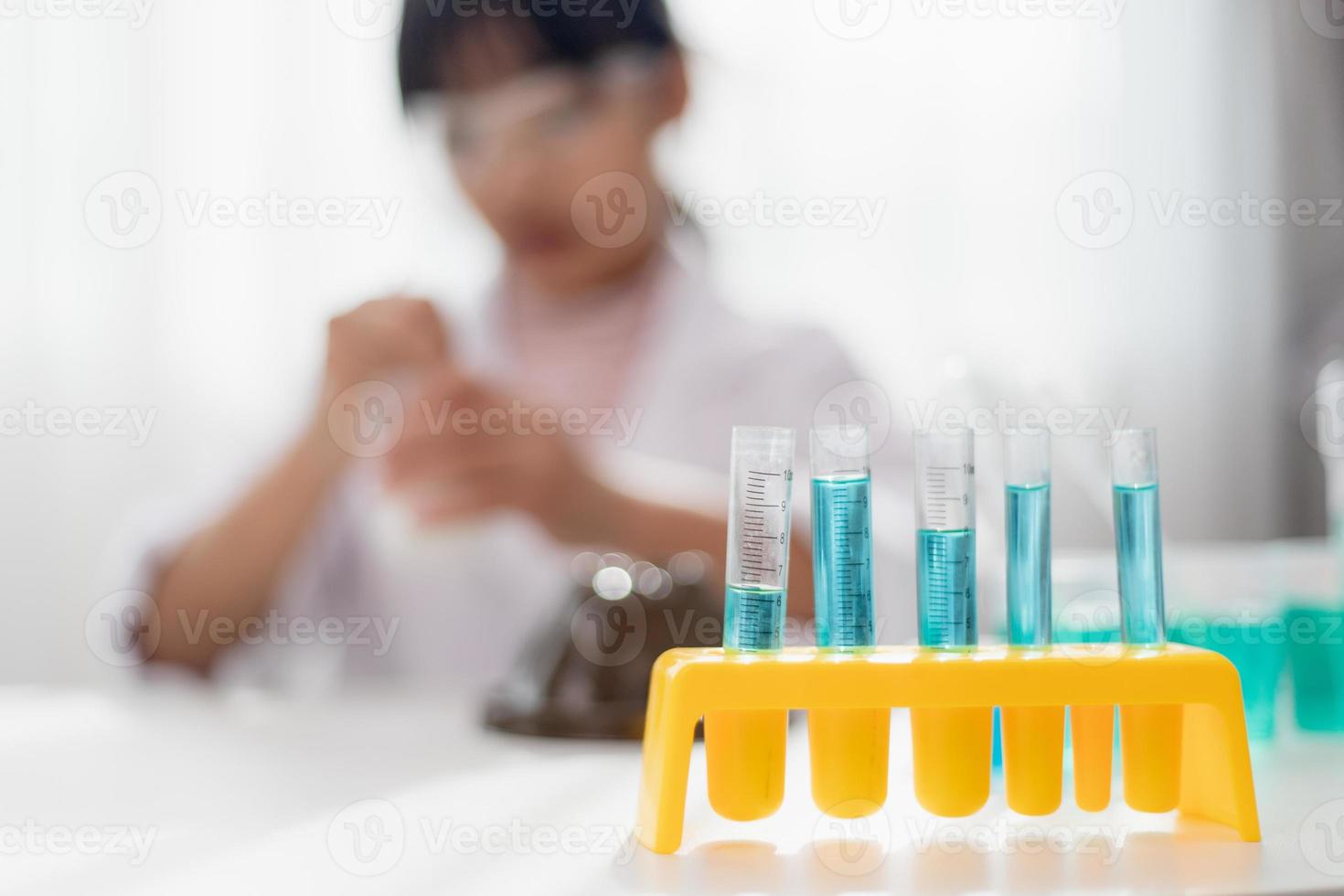 education, science, chemistry and children concept - kids or students with test tube making experiment at school laboratory photo