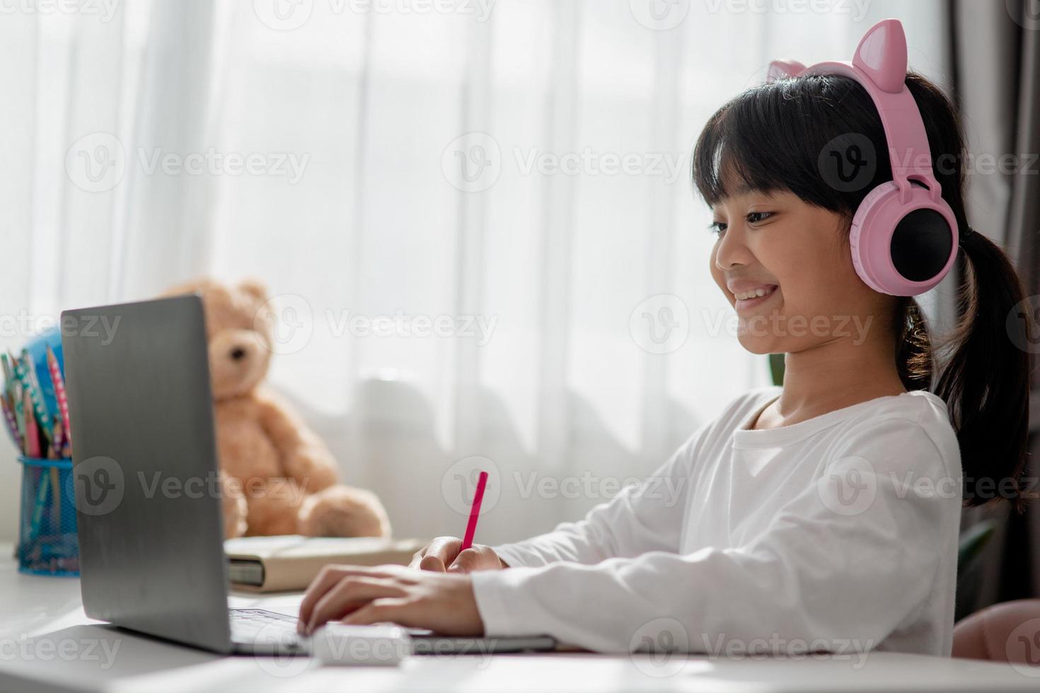 Asian little girl in headphones have video call distant class with teacher using laptop, study online on computer, homeschooling concept photo