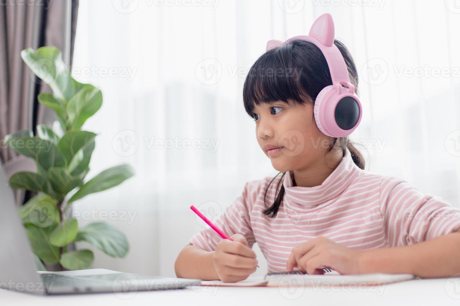 Asian little girl in headphones have video call distant class with teacher using laptop, study online on computer, homeschooling concept photo