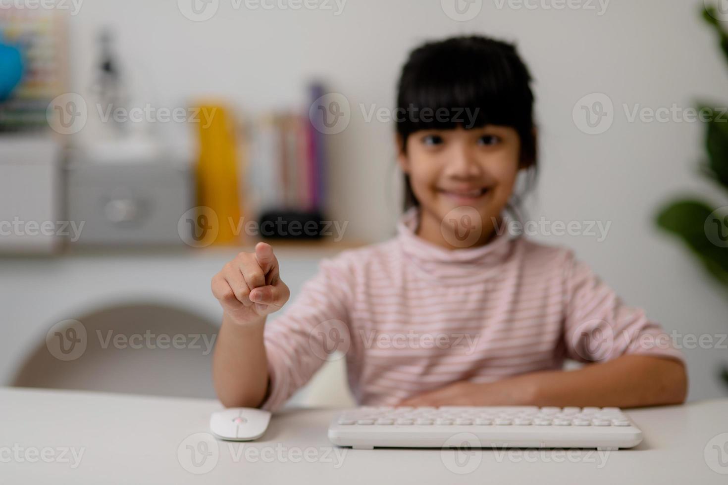 education, school, and imaginary screen concept - Asian little girl pointing in the air or imaginary screen photo