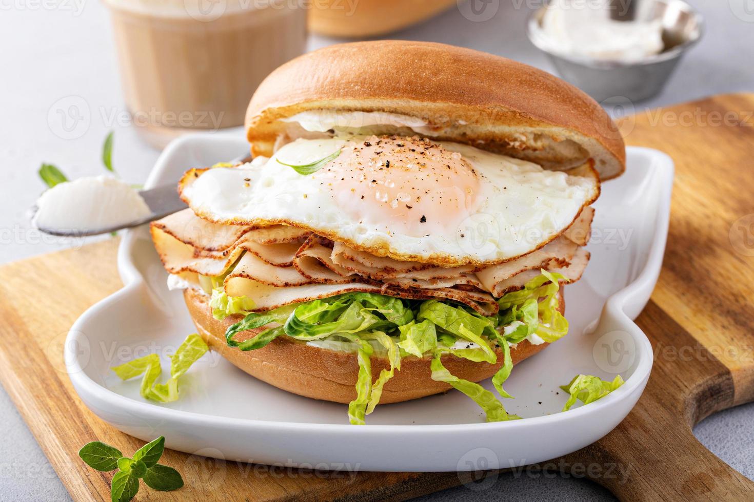 Turkey bagel breakfast sandwich with lettuce and fried egg photo