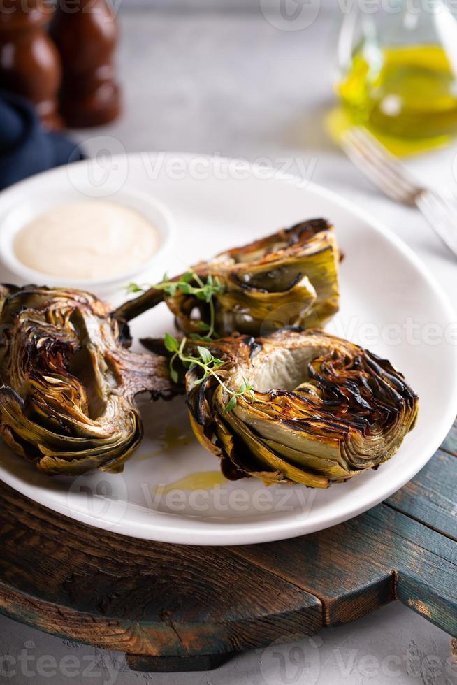 Grilled artichokes with a dipping sauce on a plate photo