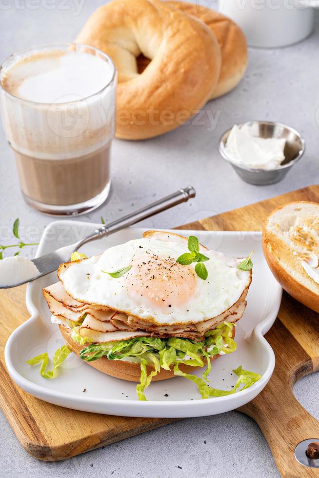 Turkey bagel breakfast sandwich with lettuce and fried egg photo