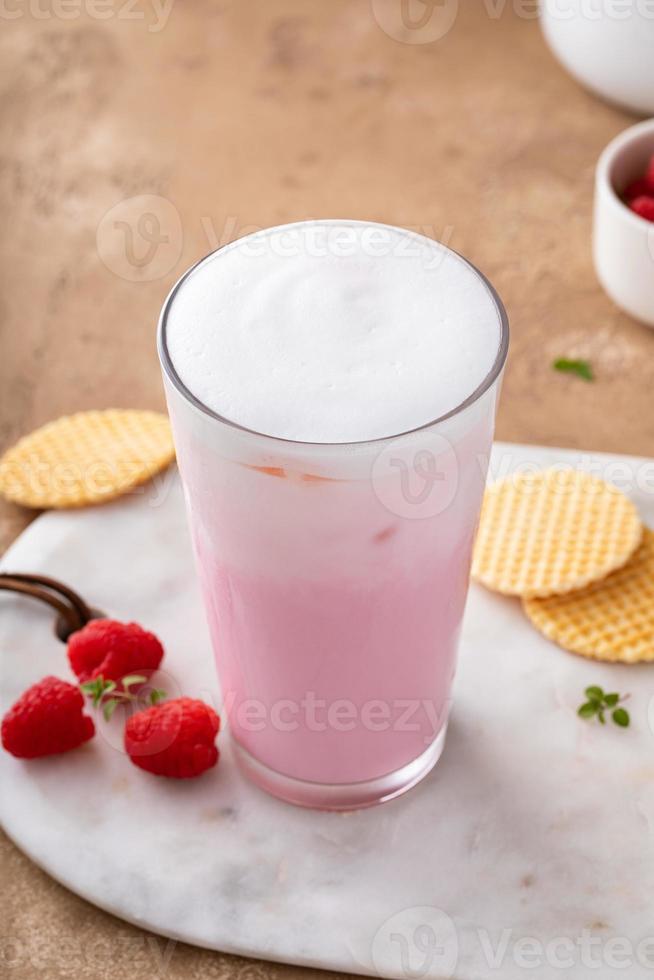 Strawberry or raspberry iced milk cocktail in a tall glass photo