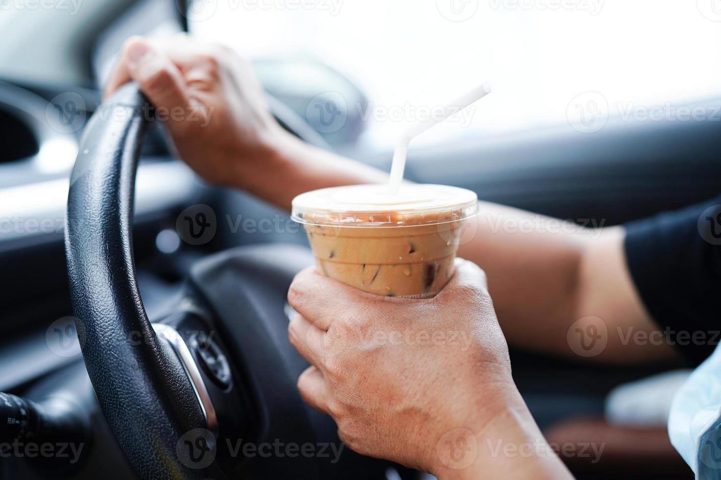 Asian woman driver hold ice coffee cup and sandwich bread for eat and drink in car, dangerous and risk an accident. photo