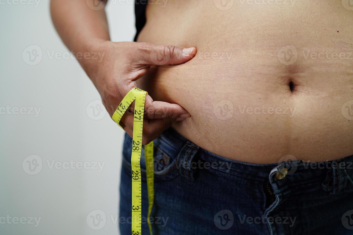 Overweight asian woman use hand to squeeze fat belly big size overweight and obesity. photo