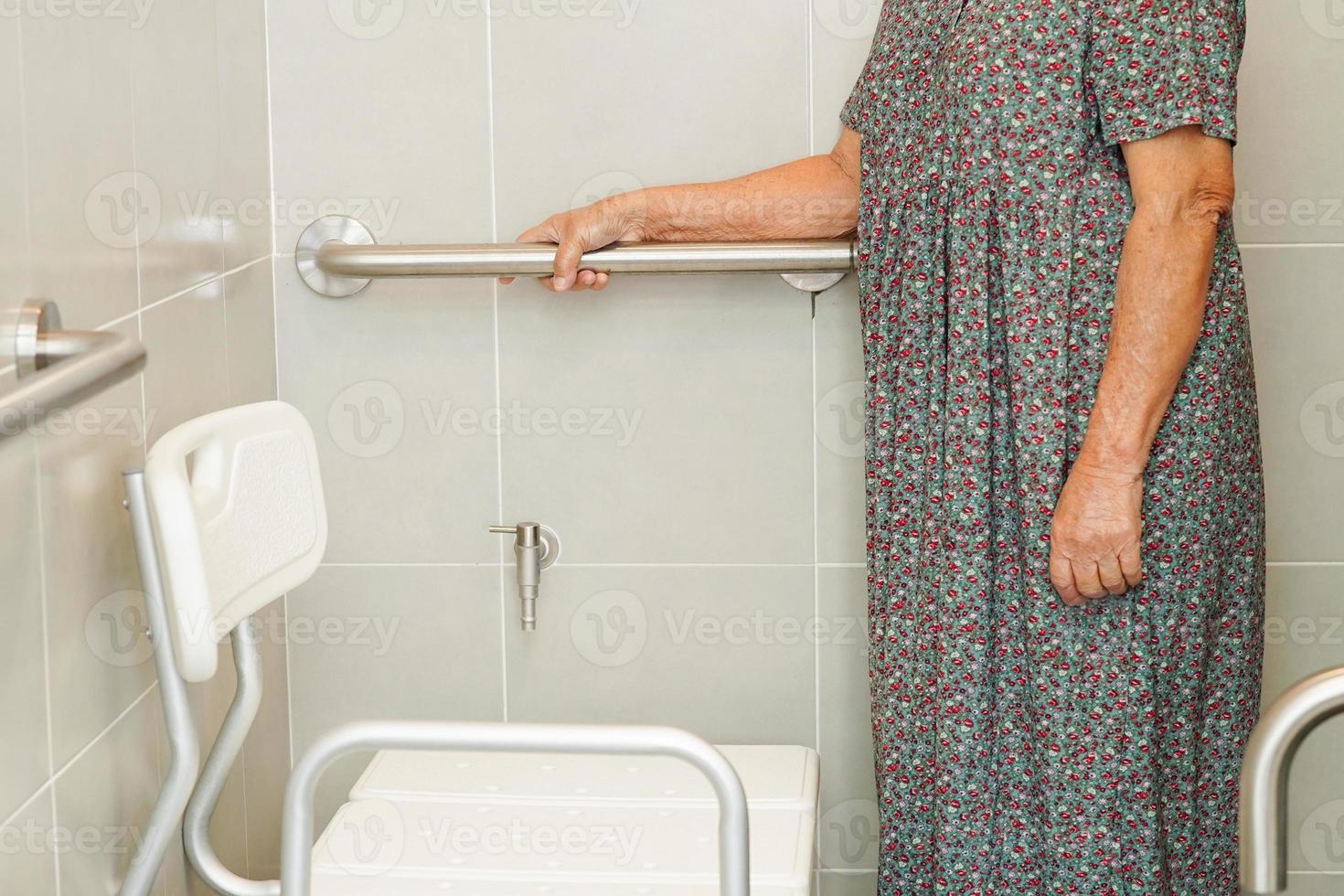 Asian elderly old woman patient use toilet support rail in bathroom, handrail safety grab bar, security in nursing hospital. photo