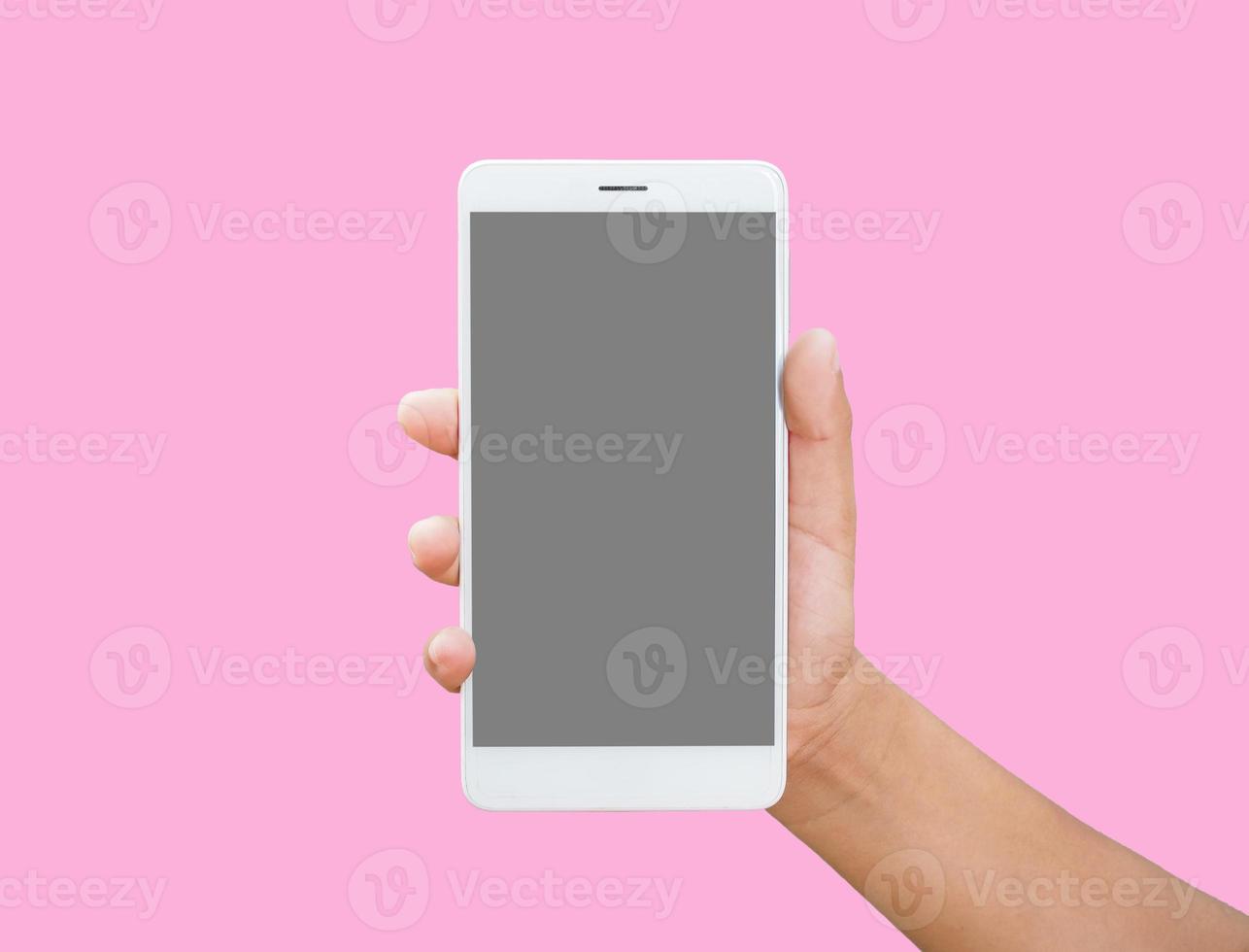 mano humana sosteniendo un teléfono inteligente de pantalla en blanco aislado en un fondo rosa. foto