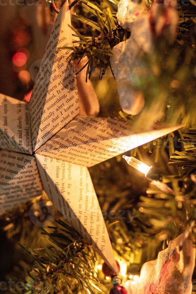 un adorno de estrella de papel colgando de un árbol de navidad con luces suaves foto