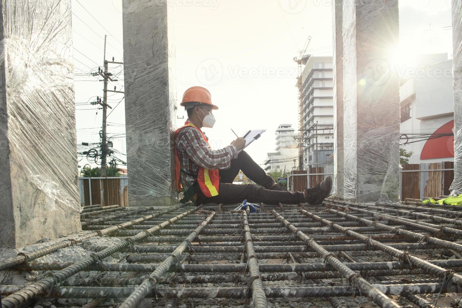 worker engenre Construction process and taking notes. Shot of a contractor filling out paperwork at a construction site. photo