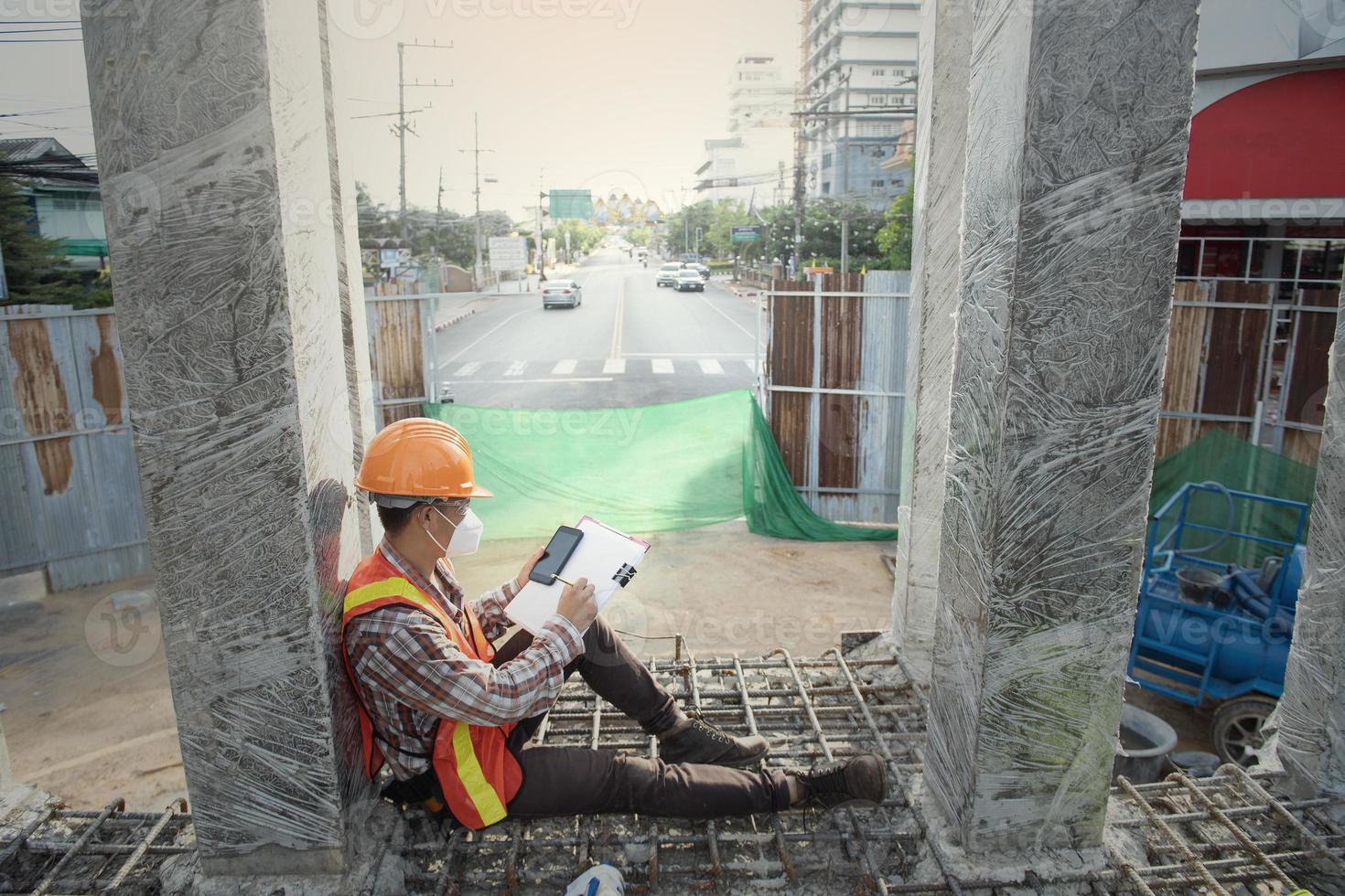 worker engenre Construction process and taking notes. Shot of a contractor filling out paperwork at a construction site. photo