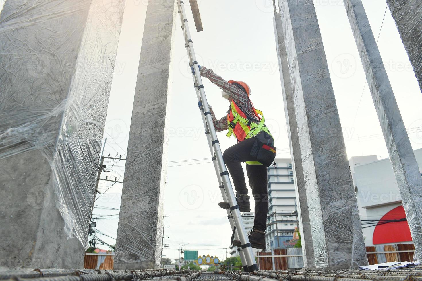 vista lateral del ingeniero trabajador en casco de seguridad subiendo la escalera para llegar a la cima. trabajador ingeniero trabajo de techado de metal para techo. foto