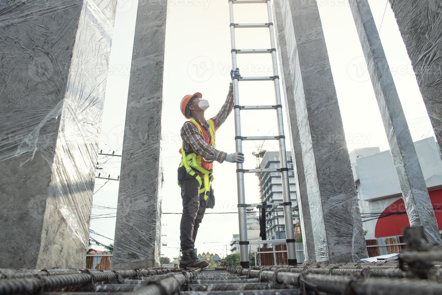 vista lateral del ingeniero trabajador en casco de seguridad subiendo la escalera para llegar a la cima. trabajador ingeniero trabajo de techado de metal para techo. foto