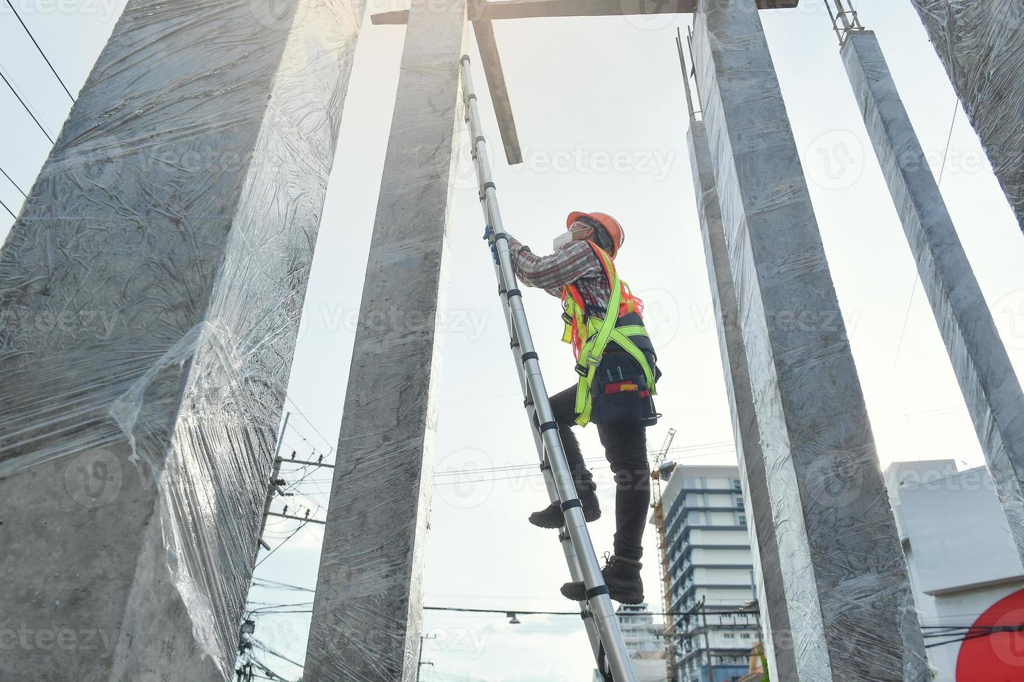 Side view of worker engineer in safety helmet climbing the ladder to get to the top . worker engineer metal roofing work for roof. photo