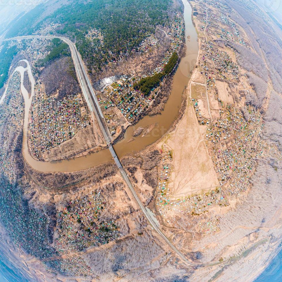 Helicopter drone shot. Aerial photography of a  over an area,  large village with small houses,, a green forest and a large field in a warm sunny summer day. Panoramic city 360  shot from above photo
