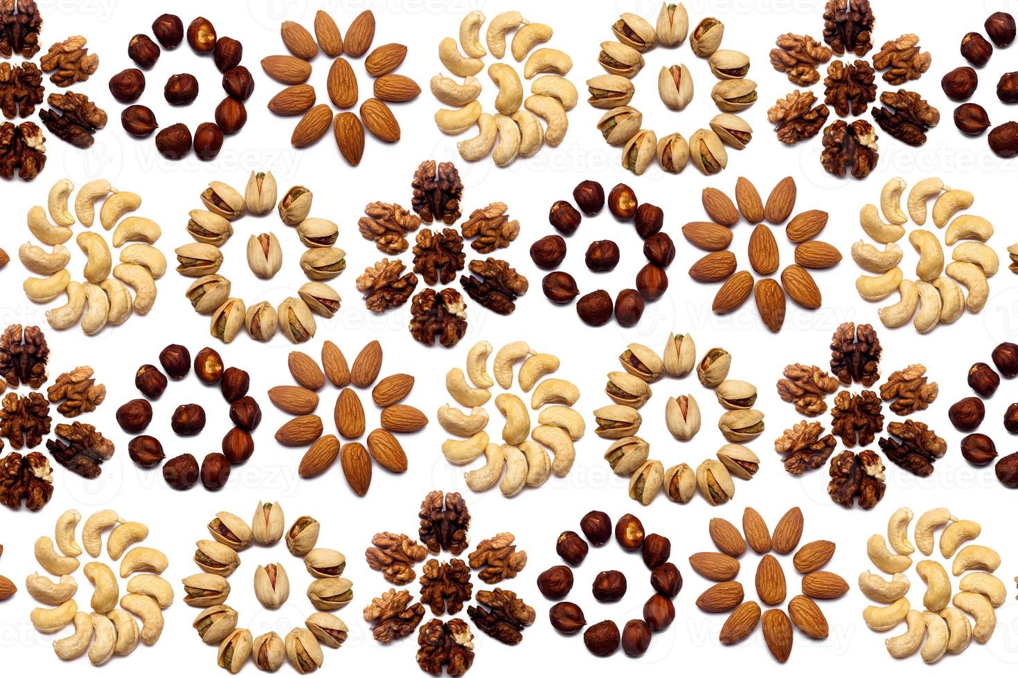 A collection of nuts made from almonds, walnuts, hazelnuts, pistachios, cashews lie in the shape of a circle or the sun on an isolated white background with a clipping path. Various nuts pattern photo