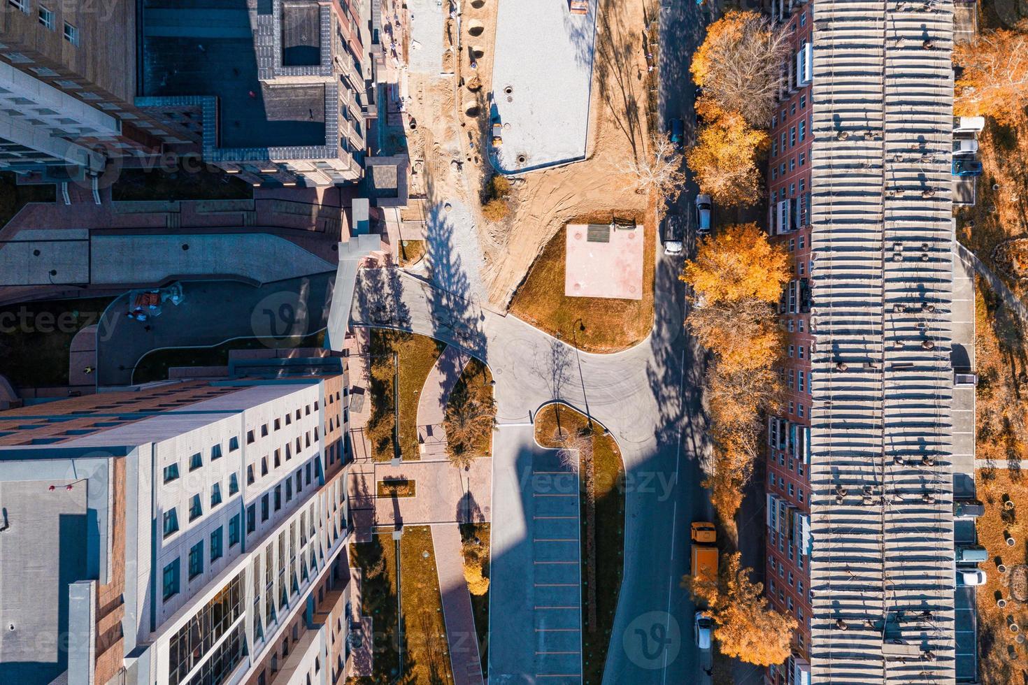 Aerial  top city view with crossroads, roads, houses, buildings, parks and parking lots in sunny autumn day. Copter drone helicopter shot. photo