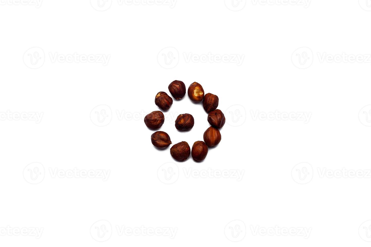 A collection of hazelnut nuts lie in the shape of a circle or sun on an isolated white background with a clipping path. Hazelnut pattern photo