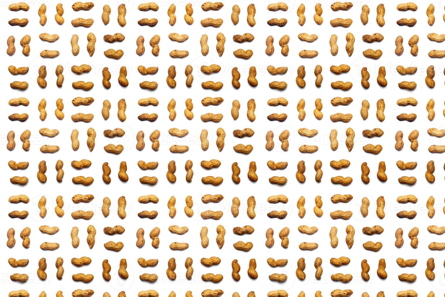 A collection of   Unpeeled peanuts   lie in straight rows along dioganals on an isolated white background. with clipping path.  Unpeeled peanuts pattern photo