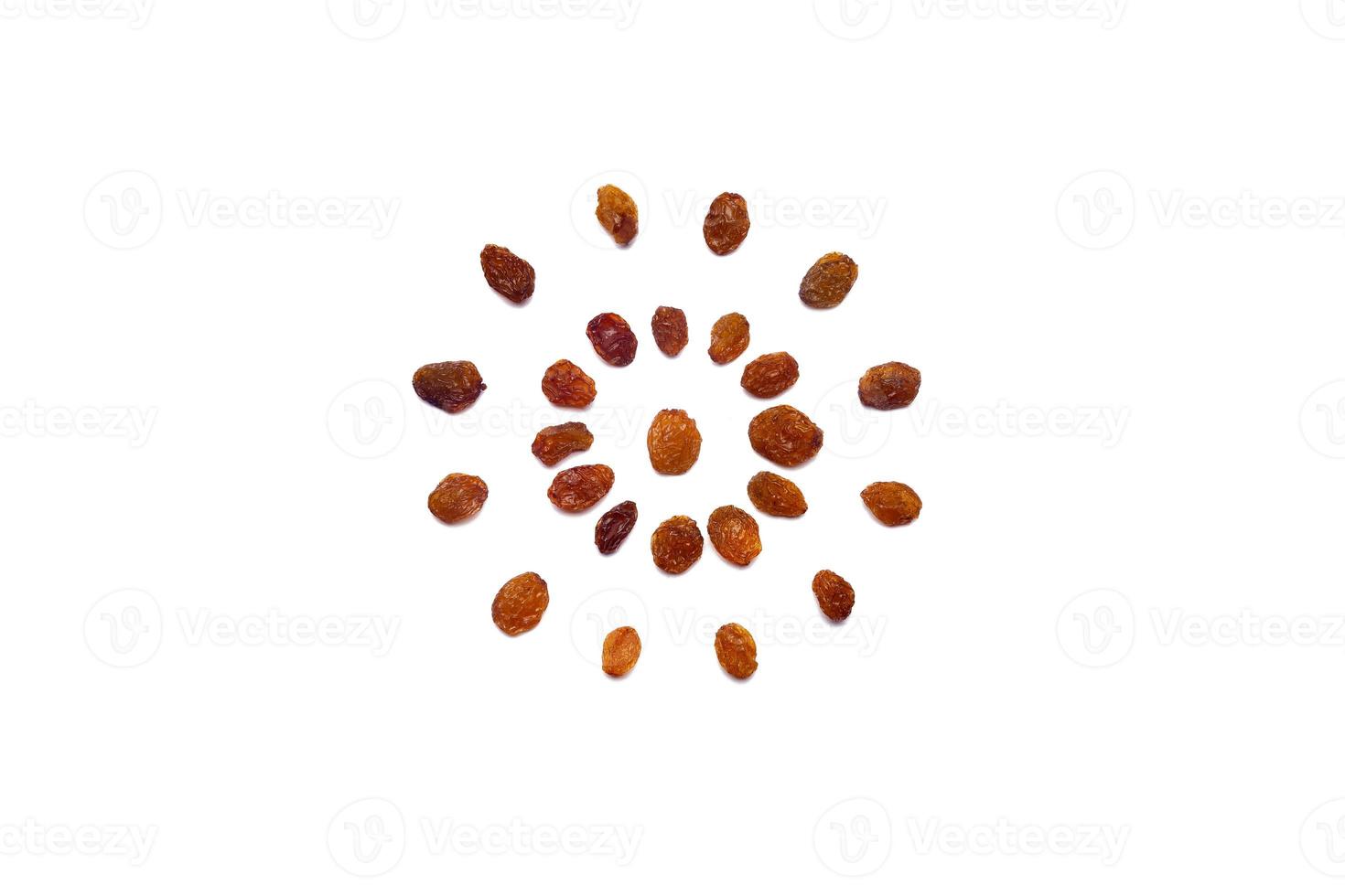 A collection of  brown raisins  lies in the shape of a circle or sun on an isolated white background with a clipping path. Brown raisins  Pattern photo