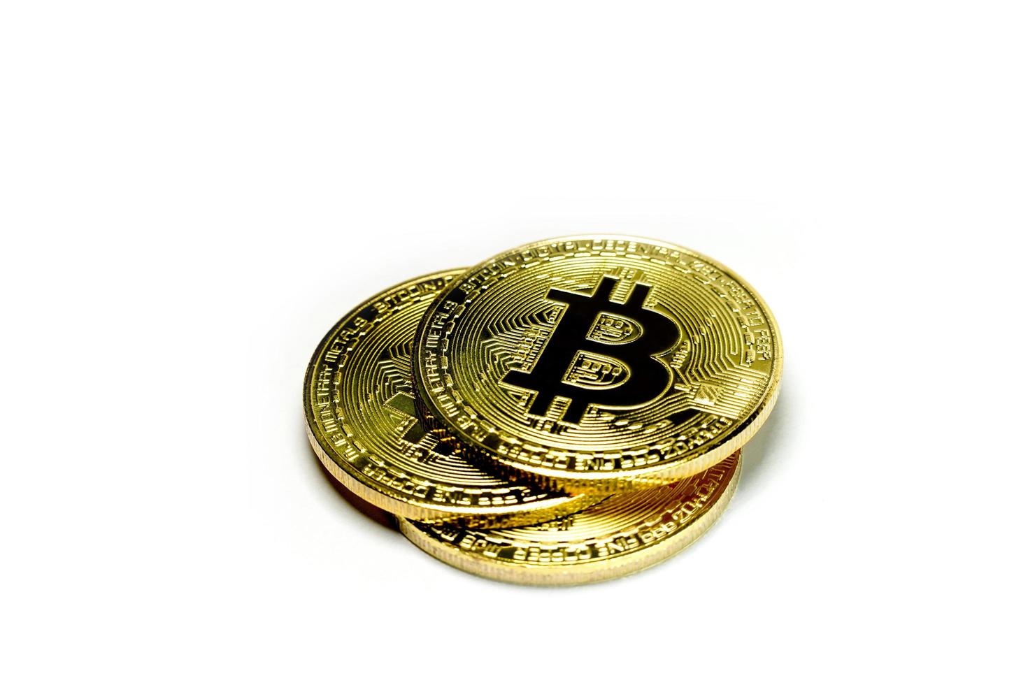 Close up of stack golden Bitcoin on white background with selective focus. Symbol of digital money coin. Three gold metal coins isolated. Virtual cryptocurrency concept. photo