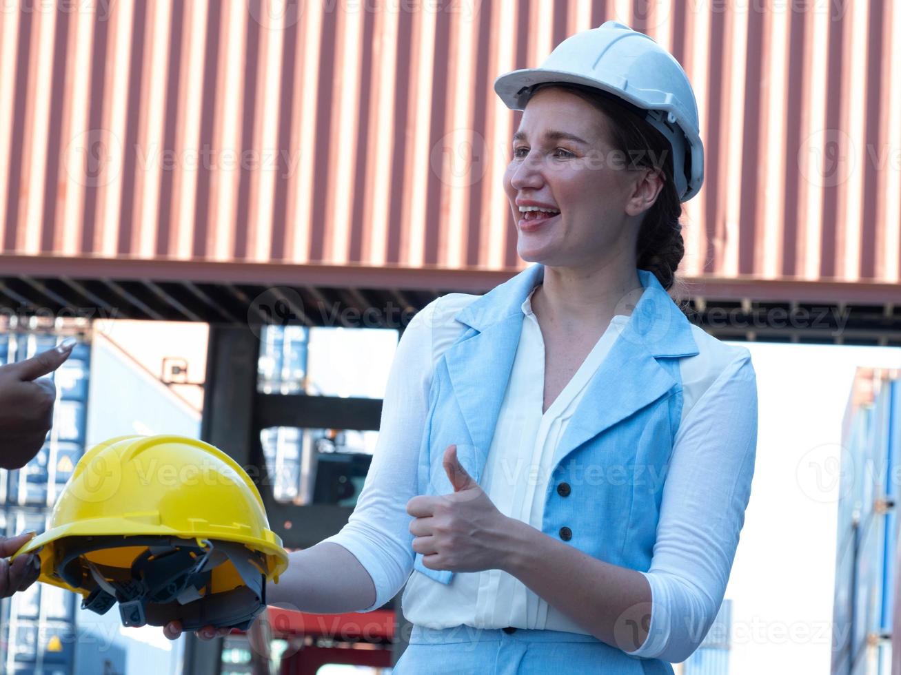 Businesswoman person candid beautiful thumb up wear white hold yellow orange color helmet hardhat safety happy smile employee staff supervisor import export negotiation container snipping country photo