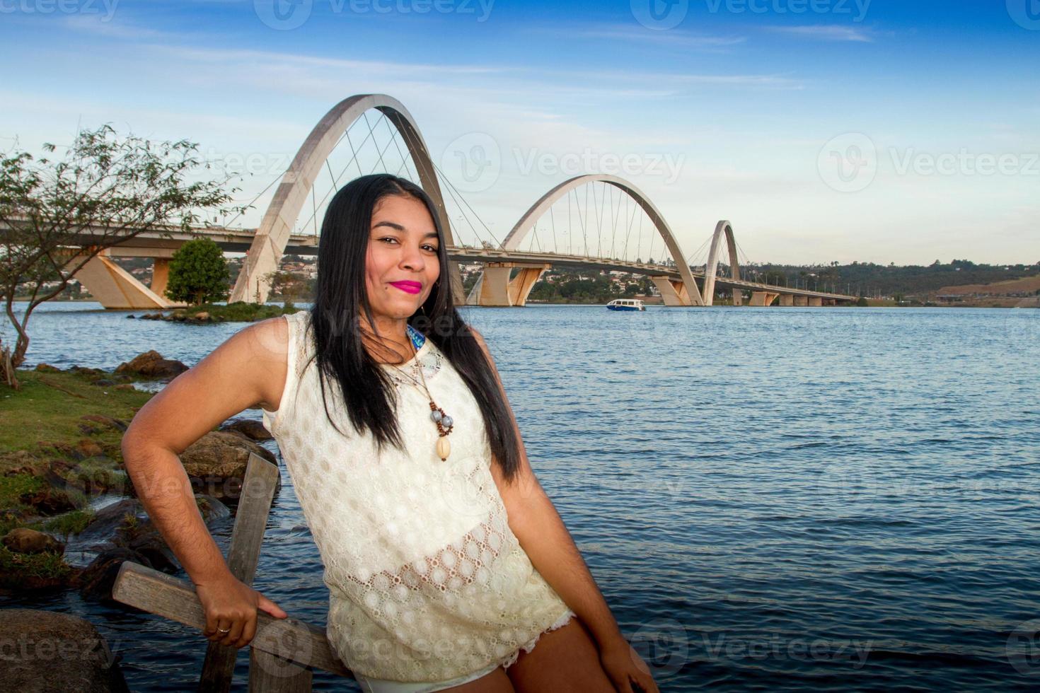 encantadora joven brasileña con una hermosa sonrisa en el parque con el puente jk en brasilia, en el fondo foto