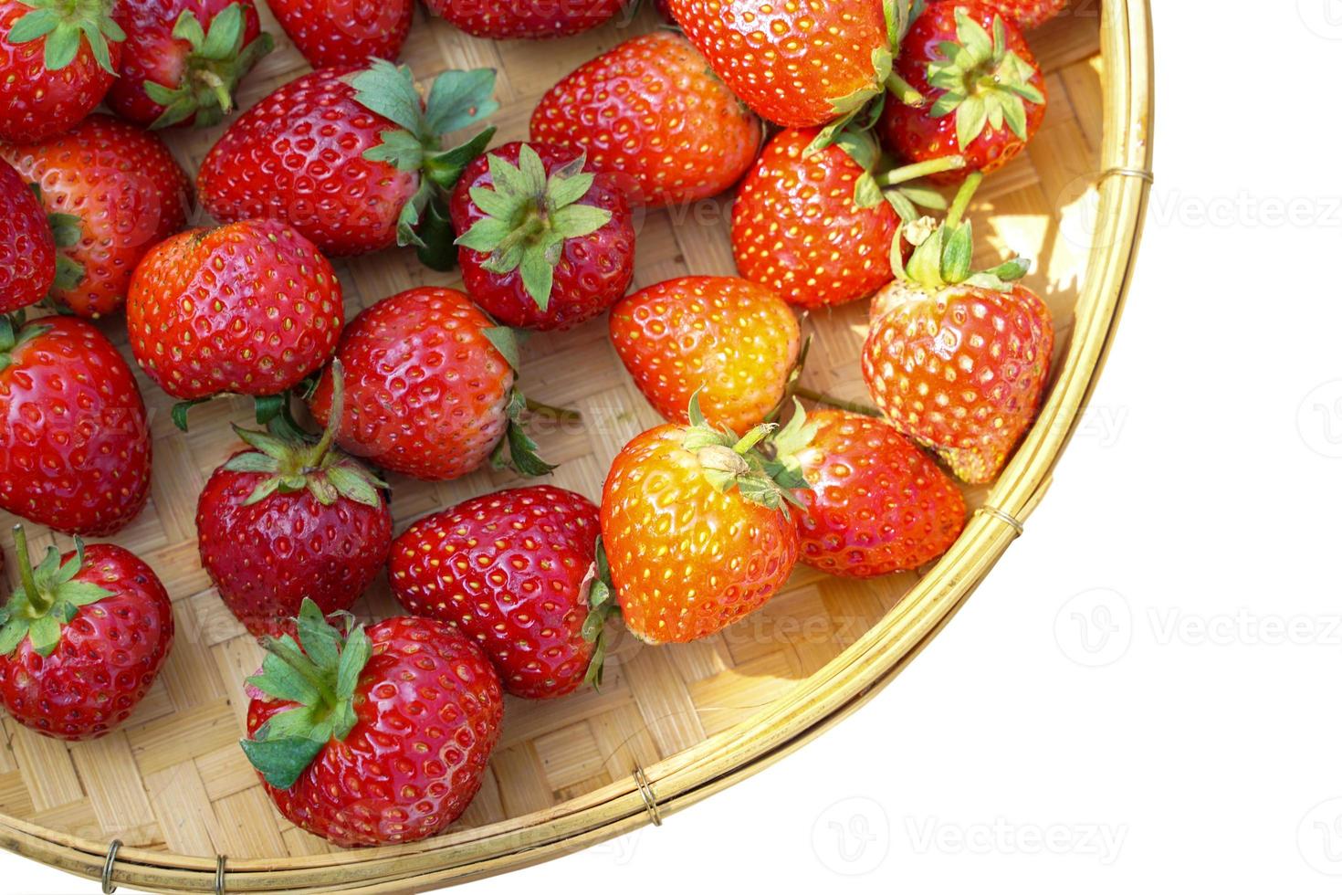 fresas rojas esparcidas en cestas de bambú sobre fondo blanco. enfoque suave y selectivo. foto