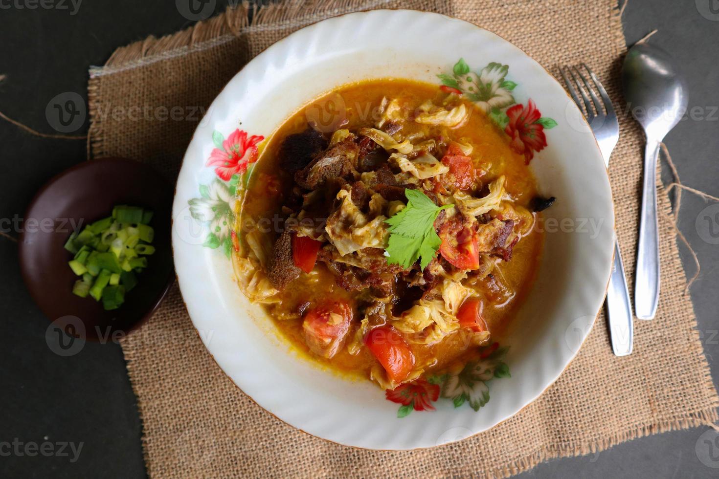 Goat Curry or gulai kambing, food from asia. Delicious goat meat curry served in a bowl.served with tomato, seasoning, celery and cabbage photo