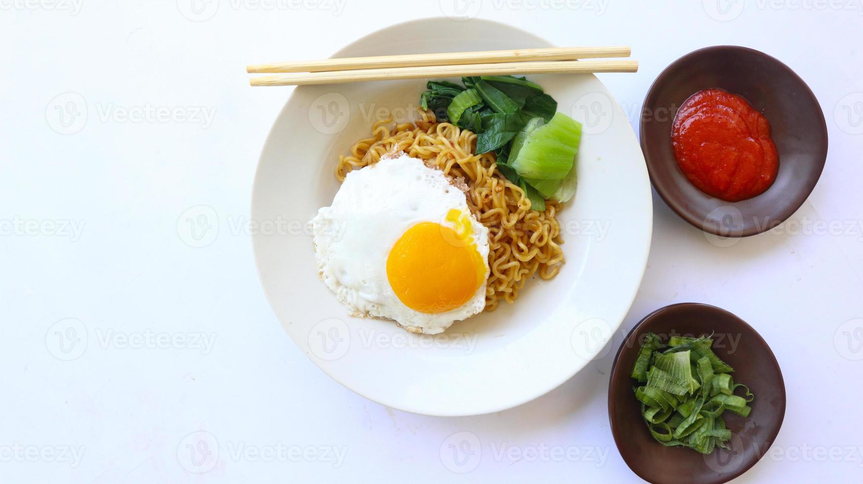 instant noodles served with egg fried and mustard greens on plate. instant fried noodle indomie photo