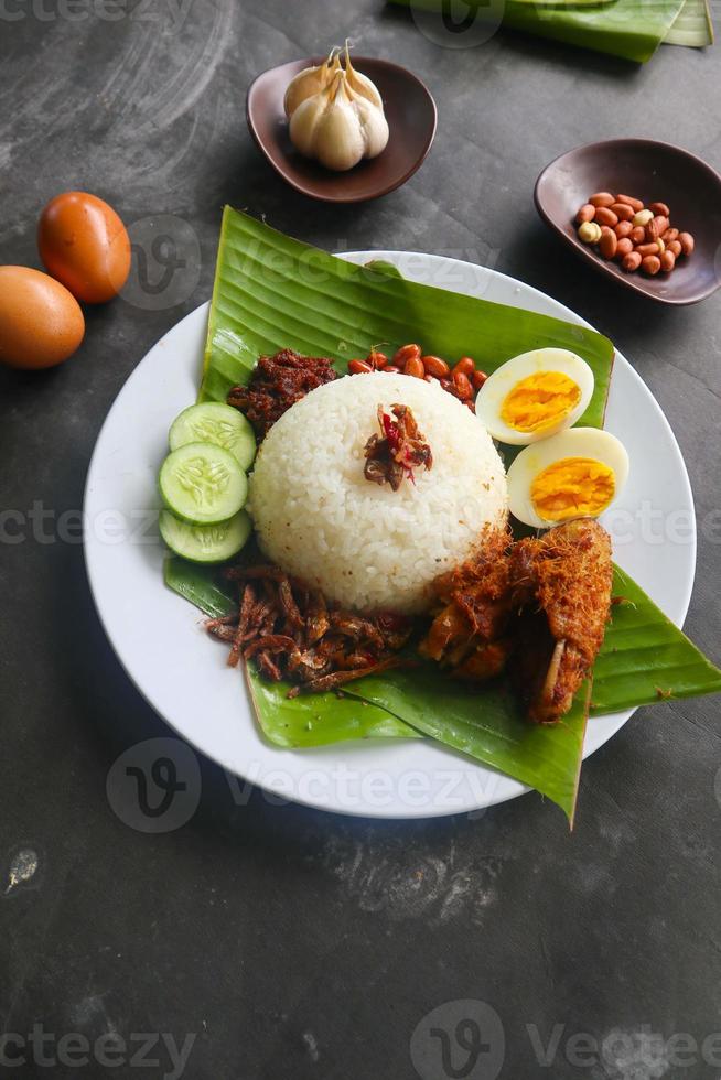 nasi lemak, is traditional malay made boiled eggs, beans, anchovies, chili sauce, cucumber. from dish served on a banana leaf photo