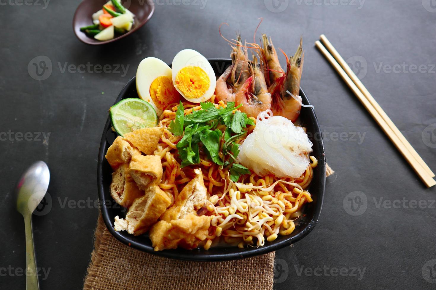 laksa, laksa curry made from vermicelli, noodles, bean sprouts, egg, tofu lime, and shrimp with a spicy soup sauce that is rich in spices. laksa served on bowl, isolated on white background. photo