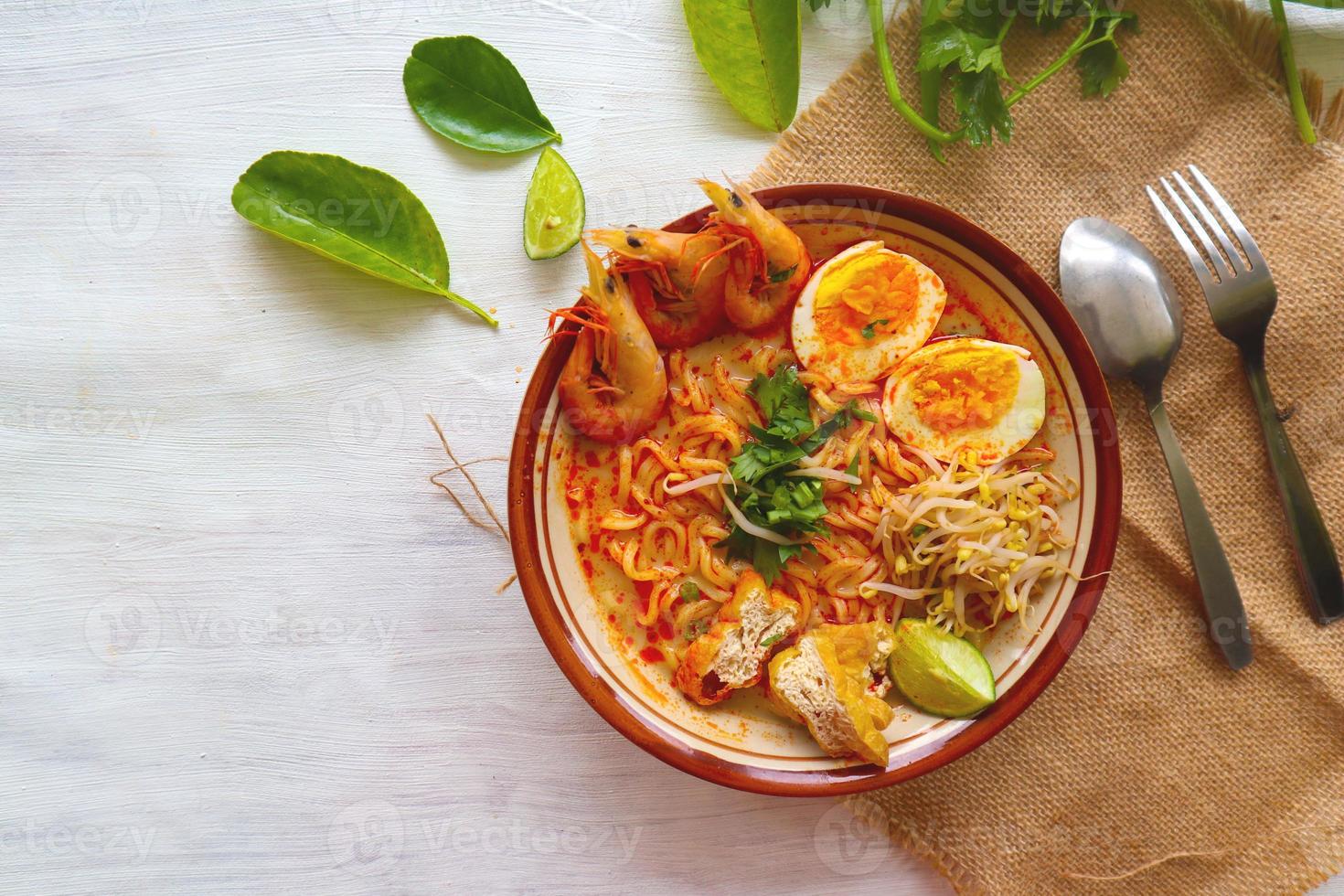 laksa, laksa curry made from vermicelli, noodles, bean sprouts, egg, tofu lime, and shrimp with a spicy soup sauce that is rich in spices. laksa served on bowl, isolated on white background. photo