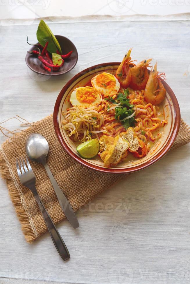 laksa, laksa curry made from vermicelli, noodles, bean sprouts, egg, tofu lime, and shrimp with a spicy soup sauce that is rich in spices. laksa served on bowl, isolated on white background. photo