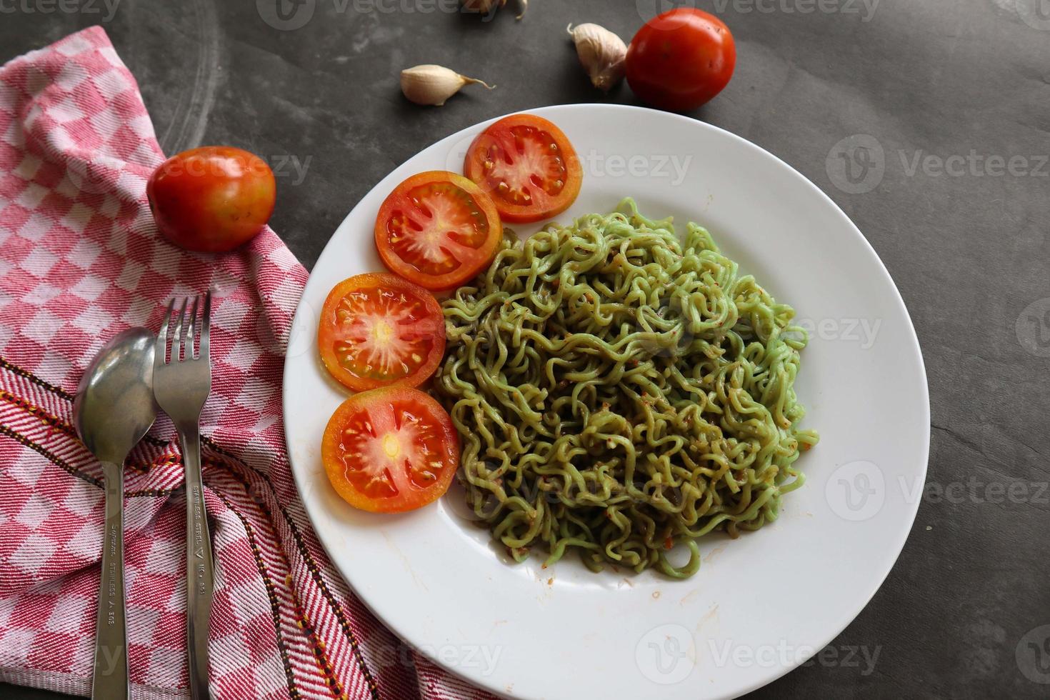 fideos verdes o pasta de espinacas, salsa de pasta vegana cruda de calabacín y tomates en un plato. foto