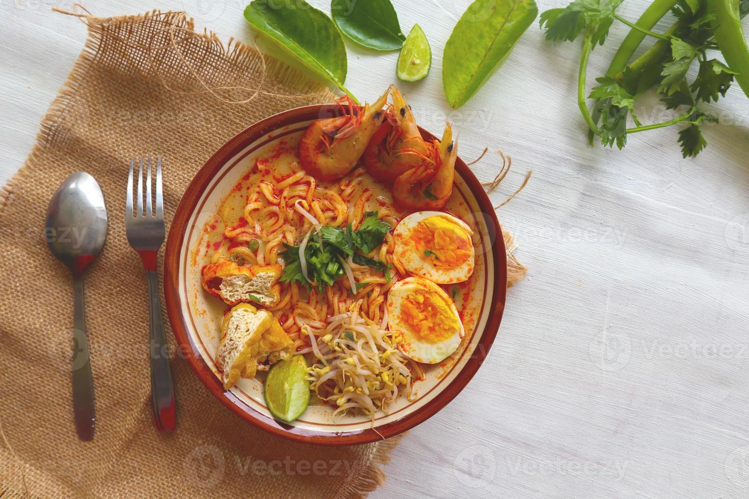 laksa, laksa curry made from vermicelli, noodles, bean sprouts, egg, tofu lime, and shrimp with a spicy soup sauce that is rich in spices. laksa served on bowl, isolated on white background. photo