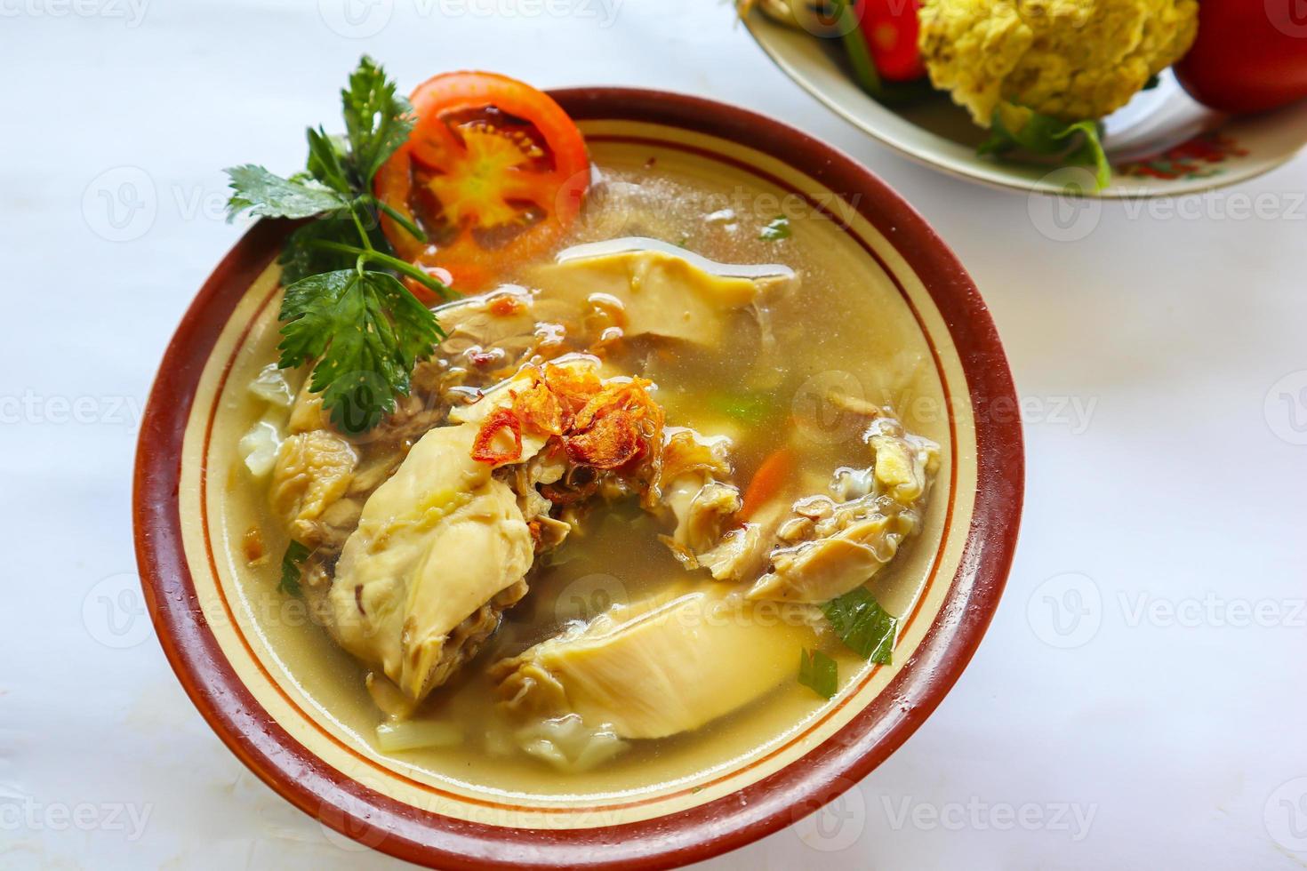Chicken soup served with vegetables, tomatoes, celery in a bowl, spoon and fork. with black background photo